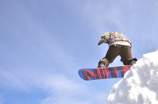 Güneşli bir günde yüksek dağlara atlayan snowboardcu.. — Stok fotoğraf