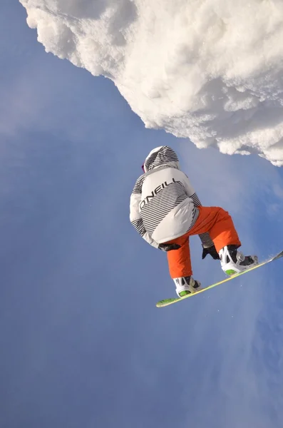 Snowboardzista podczas skoku w wysokie góry w słoneczny dzień. — Zdjęcie stockowe