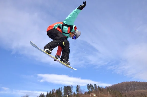 Snowboardista na skok inhigh hory za slunečného dne. — Stock fotografie
