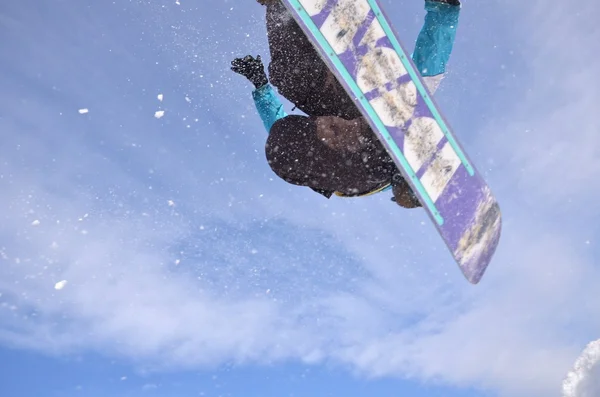 Snowboardos ugrás magas hegyekben a napsütéses napon. — Stock Fotó