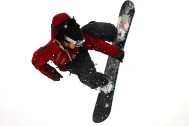 Güneşli bir günde yüksek dağlara atlayan snowboardcu..