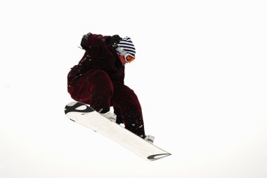 Güneşli bir günde yüksek dağlara atlayan snowboardcu..