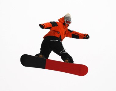 Güneşli bir günde yüksek dağlara atlayan snowboardcu..