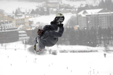 Güneşli bir günde yüksek dağlara atlayan snowboardcu..