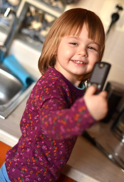 Gadis kecil berbicara dengan ponsel, latar belakang putih — Stok Foto