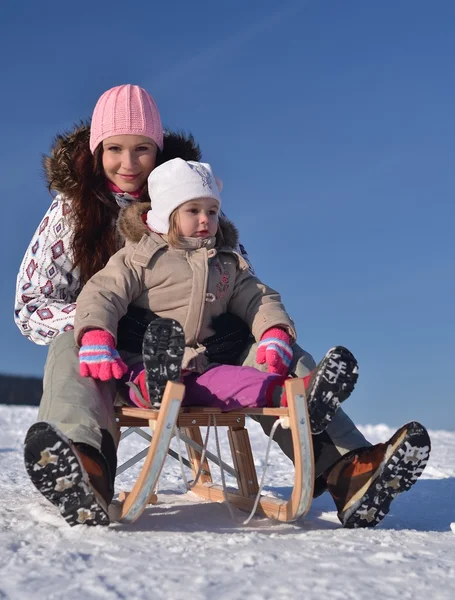 Mère est assise sur un traîneau dans le parc avec un enfant en hiver — Photo