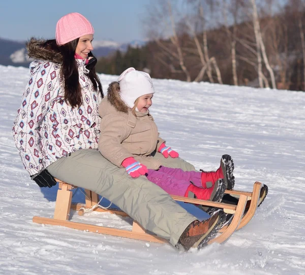 Mutter sitzt im Winter mit Kind auf Schlitten im Park — Stockfoto