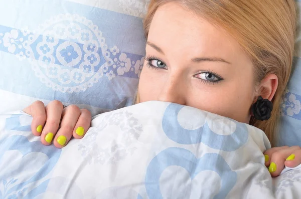 Ung vacker flicka i en säng — Stockfoto