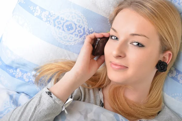 Atrakcyjna młoda kobieta rozmawia przez telefon podczas leżenia w łóżku. — Zdjęcie stockowe