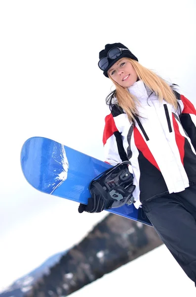 Жінка тримає сноуборд з горами на задньому плані — стокове фото