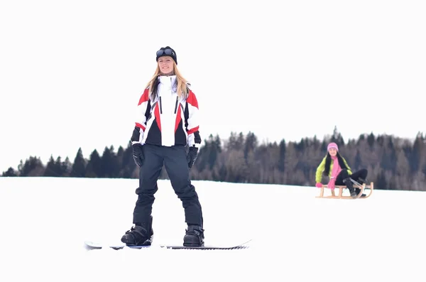 Жінка зі сноубордом, що стоїть на сніговій горі — стокове фото