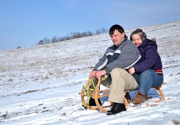 Down syndrome couple sledding — Stock Photo, Image