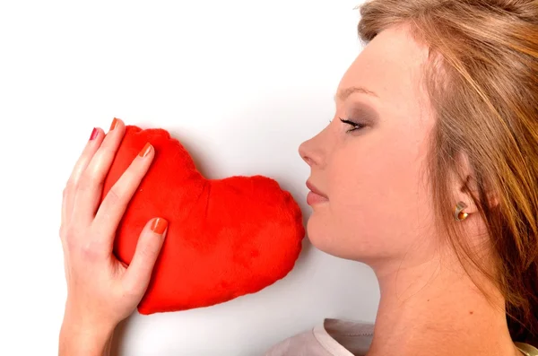Attraente giovane donna abbracciando cuscino a forma di cuore. Tutto su sfondo bianco — Foto Stock