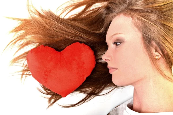 Aantrekkelijke jonge vrouw knuffelen hartvormige kussen. allemaal op witte achtergrond — Stockfoto