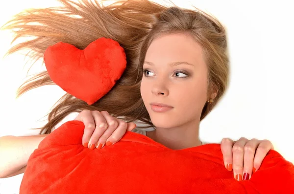 Vonzó fiatal nő átölelve szív alakú párna. fehér alapon — Stock Fotó