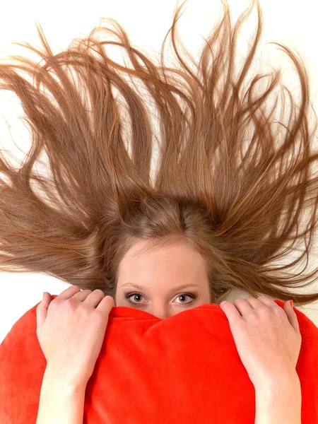 魅力的な若い女性のハート型の枕を抱いてします。白い背景の上にすべて — ストック写真