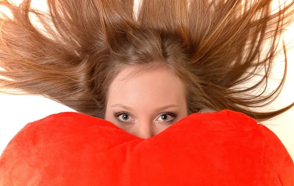 Atractiva joven mujer abrazando almohada en forma de corazón. Todo sobre fondo blanco —  Fotos de Stock