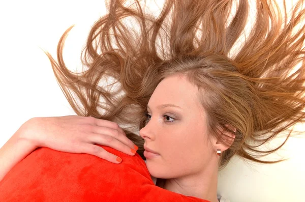 魅力的な若い女性のハート型の枕を抱いてします。白い背景の上にすべて — ストック写真