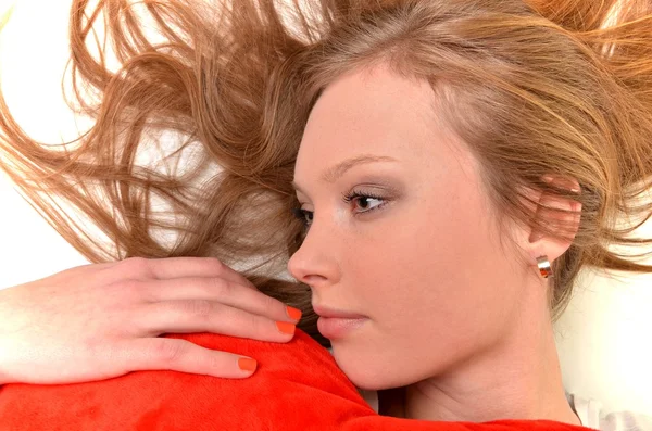 Привлекательная молодая женщина обнимает подушку в форме сердца. Все на белом фоне — стоковое фото
