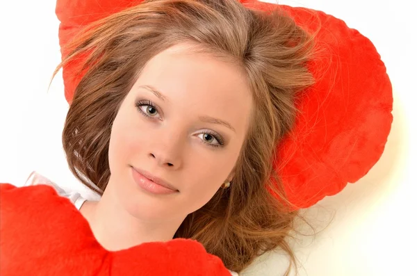 Atractiva joven mujer abrazando almohada en forma de corazón. Todo sobre fondo blanco — Foto de Stock