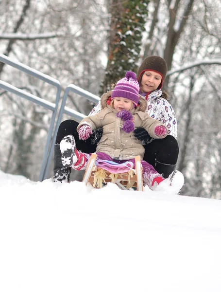 Äiti ja tytär kelkkailu, mukava talvi kohtaus — kuvapankkivalokuva