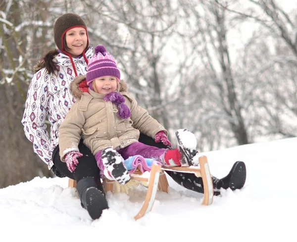 Мати і дочка катаються на санях, гарна зимова сцена — стокове фото