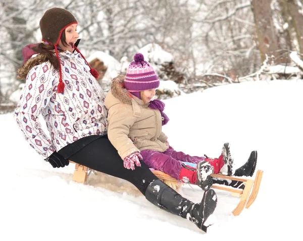 Мати і дочка катаються на санях, гарна зимова сцена — стокове фото