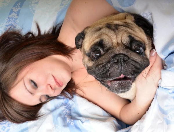 Mulher com pug na cama — Fotografia de Stock