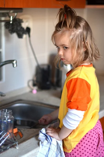 Малыш моет посуду на кухне — стоковое фото