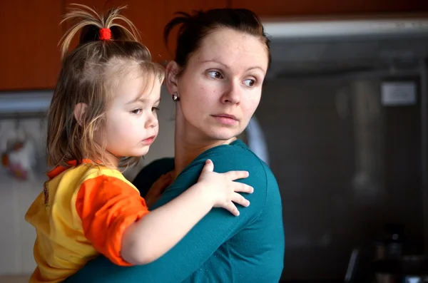 Matka, trzymając dziecko w ramionach w kuchni — Zdjęcie stockowe