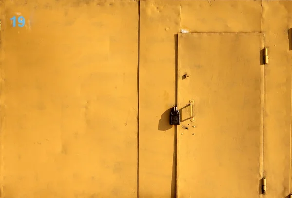 Porta de garagem de ferro amarelo brilhante com um cadeado — Fotografia de Stock