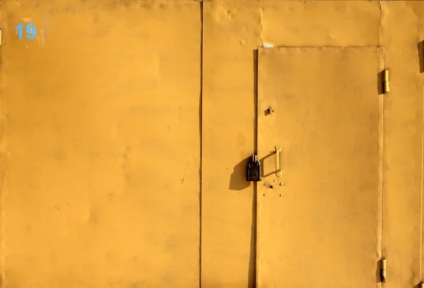 stock image Bright yellow iron garage door with a padlock