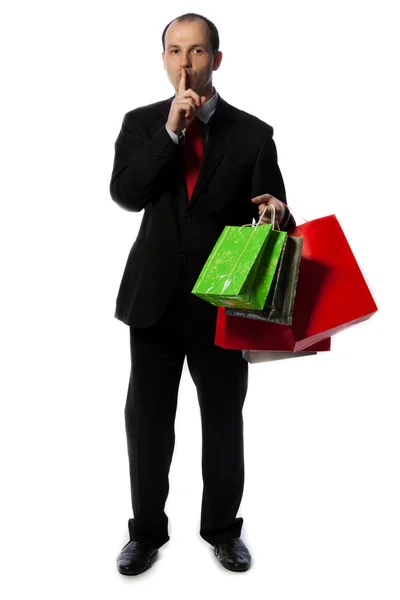 Businessman with shopping bags and making quiet sign with hand — Stock Photo, Image