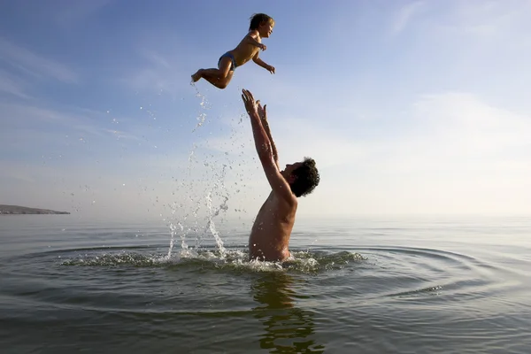 Father is tossing up a child in water — Stock Photo, Image