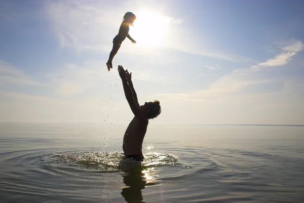 Padre está arrojando a un niño en el agua — Foto de Stock