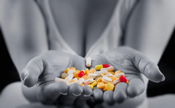 Pilules colorées dans les mains des femmes — Photo