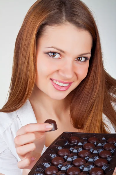 Όμορφη νεαρή γυναίκα τρώει σοκολάτες — Φωτογραφία Αρχείου