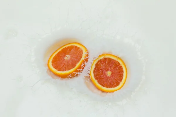Orange and splashing milk — Stock Photo, Image