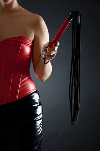 Frau in rotem Lederkorsett mit Peitsche — Stockfoto