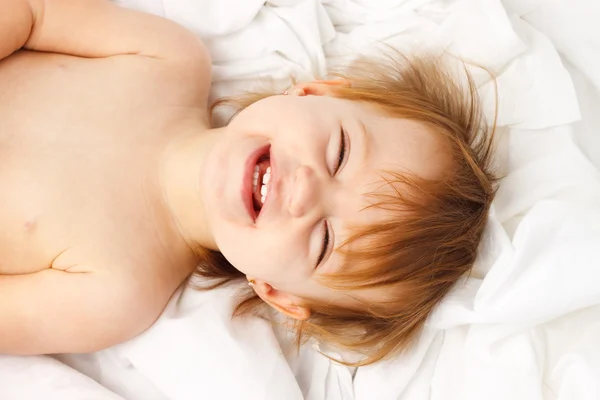 Położyć dziecko białego arkusza śmiech — Zdjęcie stockowe