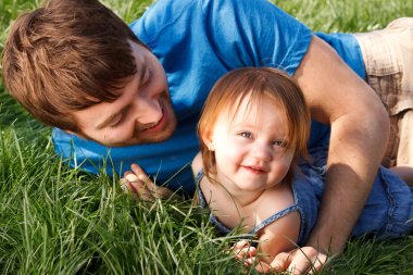 Happy Father And Daughter Laying In Grass clipart