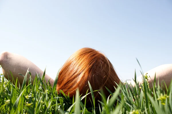 红头发的女人躺在草向上看 — 图库照片