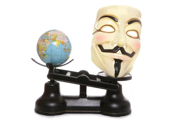 stock image Guy fawkes mask on scales with a globe