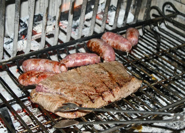 Carne grelhada fatiada com salsichas em lareira — Fotografia de Stock