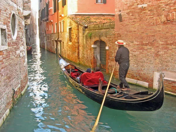 Gondolier in a gondola along a canal — Stock Photo, Image