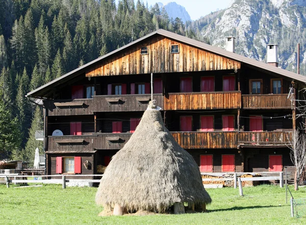 Pila di erba secca e una tipica casa delle Dolomiti — Foto Stock