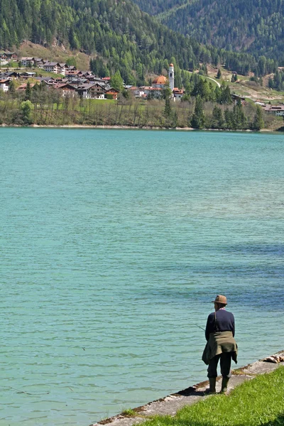 Old fisherman to fish in a blue Lake — Stock Photo, Image