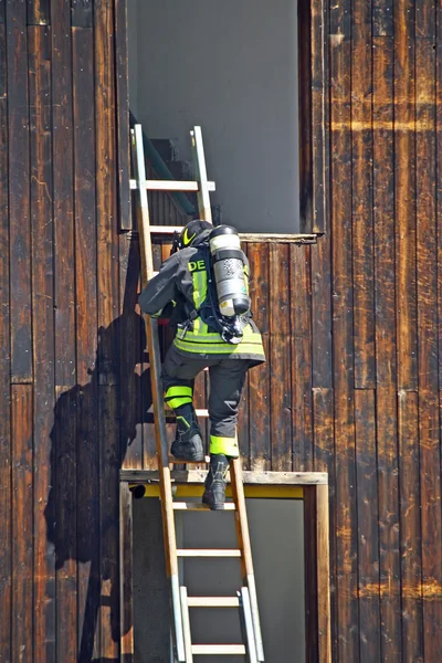 Пожежник з кисневим циліндром, щоб прив'язати драбину до гасіння — стокове фото