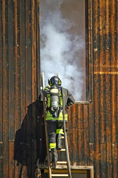 Firefighters with oxygen cylinder to peg up the ladder to exting — Stock Photo, Image