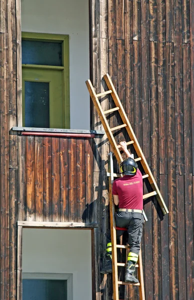 Feuerwehrmann steigt auf Leiter, um auf Gebäude zu klettern — Stockfoto